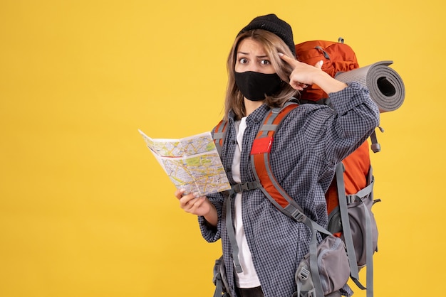 Vista frontale della ragazza del viaggiatore confuso con maschera nera e mappa della holding dello zaino