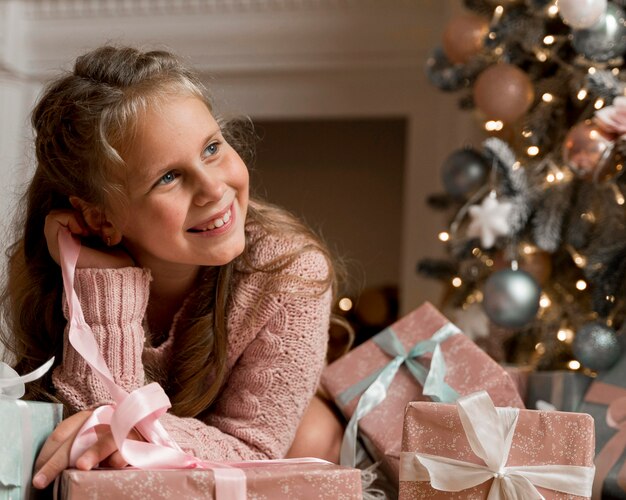 Vista frontale della ragazza felice con regali e albero di Natale