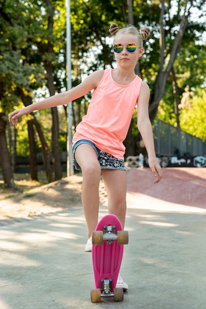 Vista frontale della ragazza su skateboard rosa