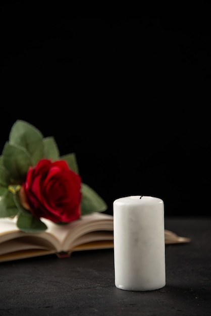 Vista frontale della rosa rossa con libro aperto e candela su nero