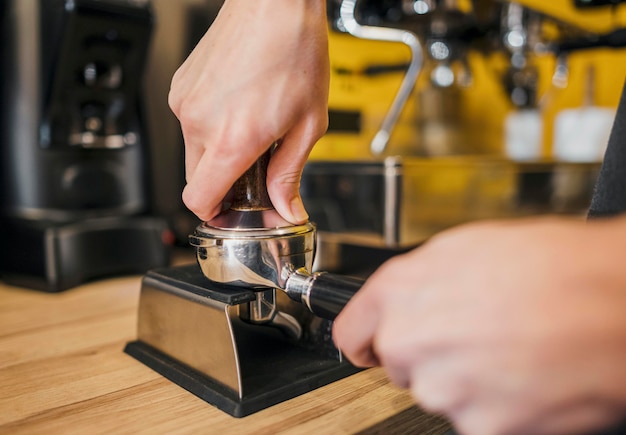 Vista frontale della tazza di riempimento barista con caffè per macchina