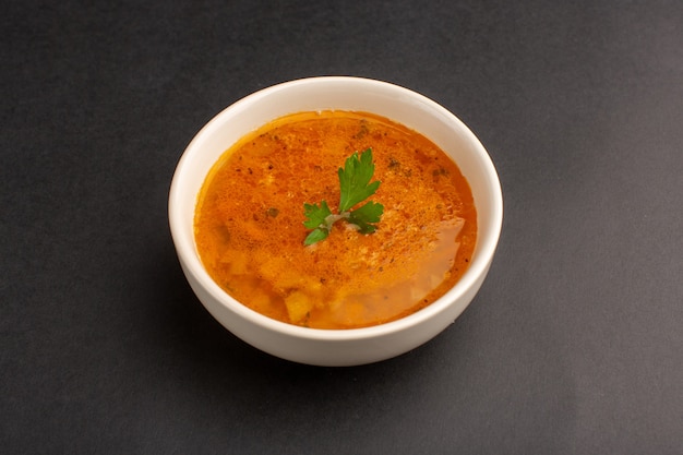 Vista frontale della zuppa deliziosa all'interno del piatto sul piatto del pasto cena cibo minestra scrivania scura