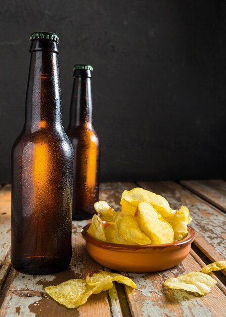 Vista frontale delle bottiglie di vetro di birra con patatine