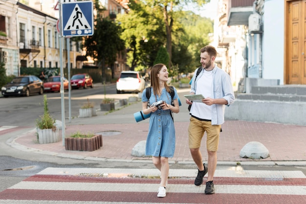 Vista frontale delle coppie turistiche con la mappa e la macchina fotografica sull'attraversamento