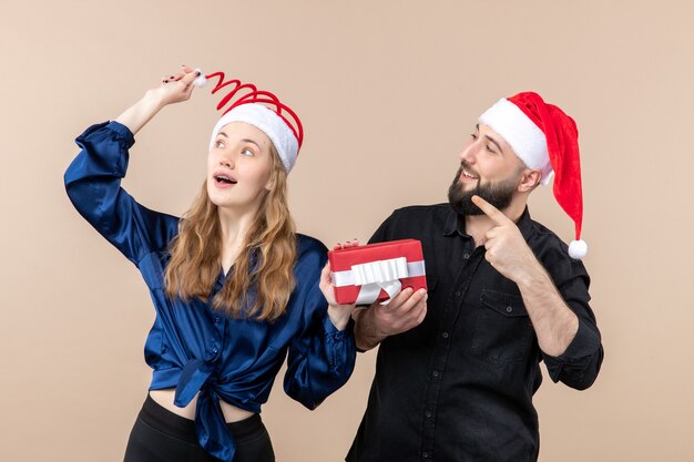 Vista frontale delle giovani coppie che tengono entrambi i maschi presenti sullo sfondo rosa regalo vacanza foto capodanno natale