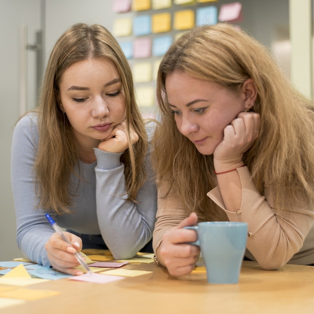 Vista frontale delle idee di scrittura della donna sulle note appiccicose all'ufficio