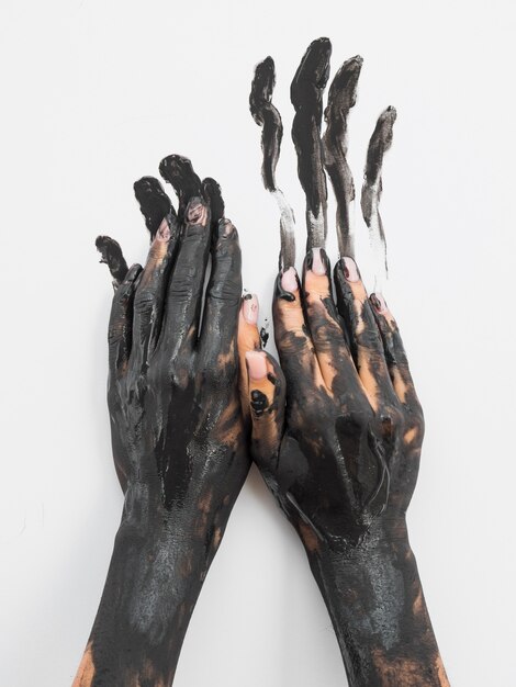 Vista frontale delle mani dipinte con vernice nera
