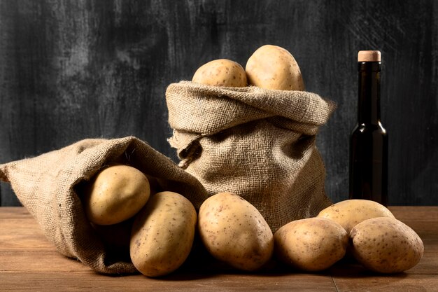 Vista frontale delle patate nel sacco di iuta con bottiglia di olio