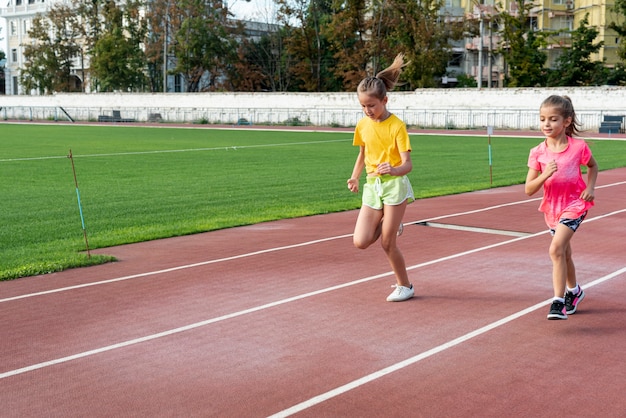 Vista frontale delle ragazze che corrono in pista