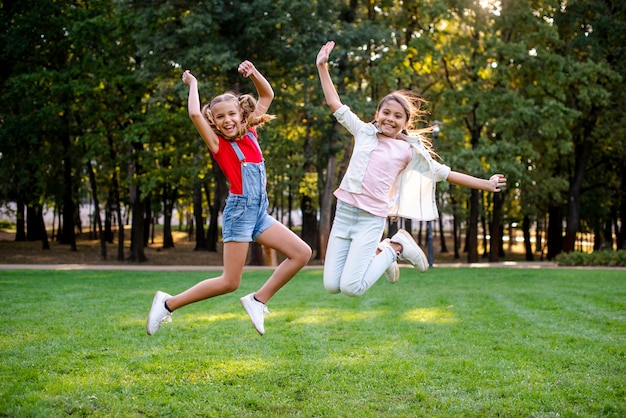 Vista frontale delle ragazze che saltano nel parco