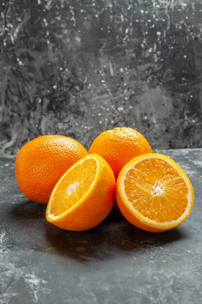 Vista frontale di arance fresche organiche naturali intere e tagliate allineate in due file su sfondo scuro