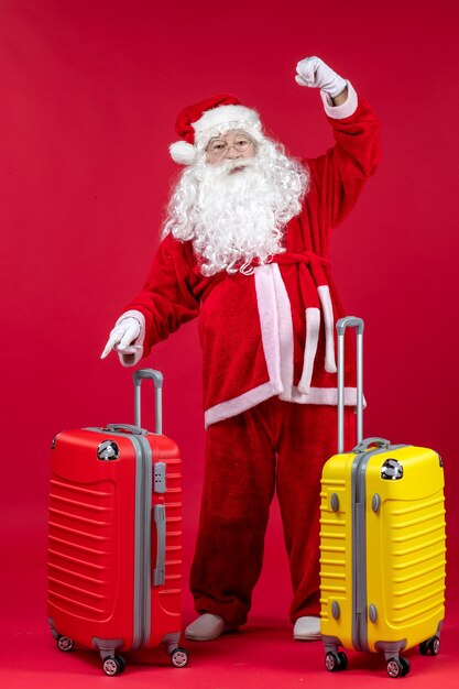 Vista frontale di Babbo Natale con due sacchi che si preparano per il viaggio sulla parete rossa