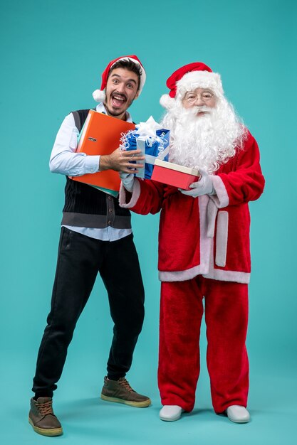 Vista frontale di Babbo Natale con giovane maschio e regali sulla parete blu