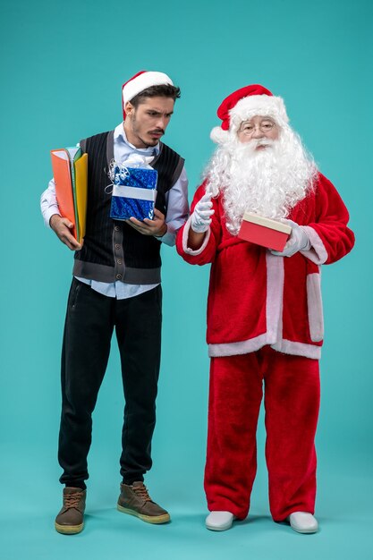 Vista frontale di Babbo Natale con giovane maschio e regali sulla parete blu