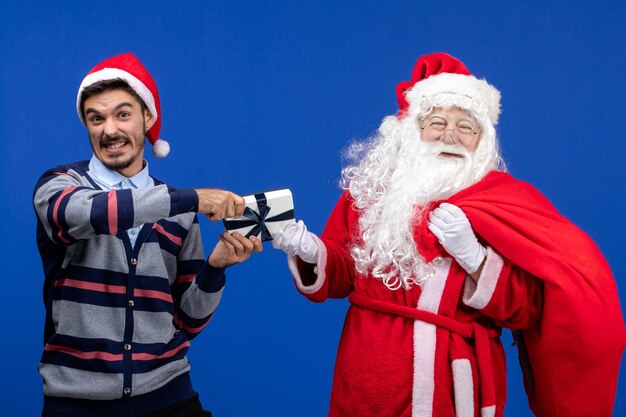 Vista frontale di babbo natale con il giovane che tiene presente sul muro blu