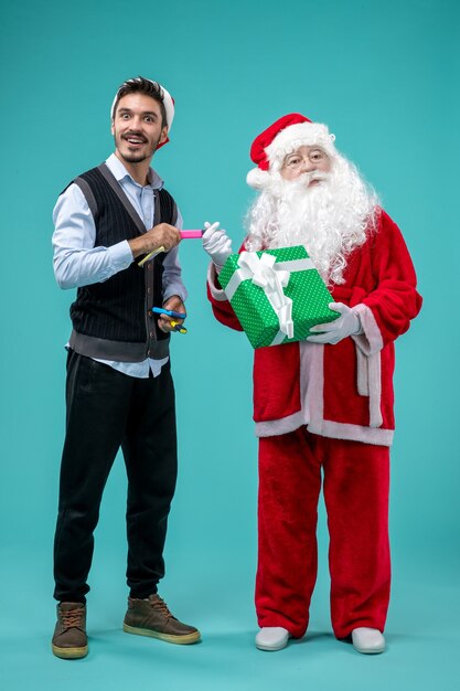 Vista frontale di Babbo Natale con il giovane e presente sulla parete blu