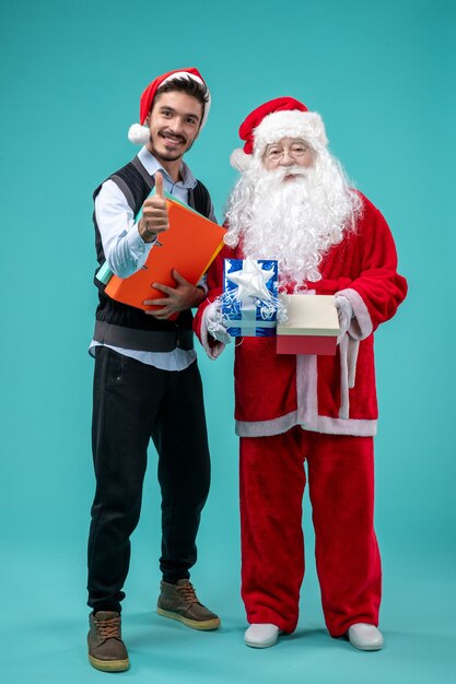 Vista frontale di Babbo Natale con il giovane e regali sulla parete blu