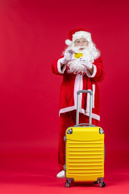 Vista frontale di Babbo Natale con il sacchetto giallo che tiene la carta di credito gialla sulla parete rossa