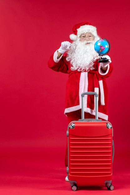 Vista frontale di Babbo Natale con la borsa che si prepara per il viaggio sulla parete rossa