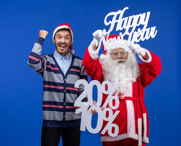 Vista frontale di Babbo Natale con un giovane che tiene in mano Felice Anno Nuovo e numeri scritti sul muro blu