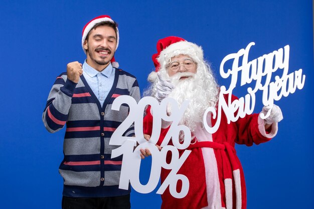 Vista frontale di Babbo Natale con un giovane che tiene in mano Felice Anno Nuovo e scritte in percentuale sulla parete blu