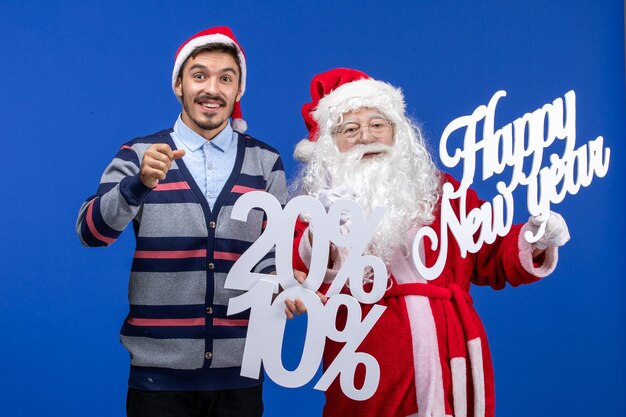 Vista frontale di Babbo Natale con un giovane che tiene in mano Felice Anno Nuovo e scritte in percentuale sulla parete blu
