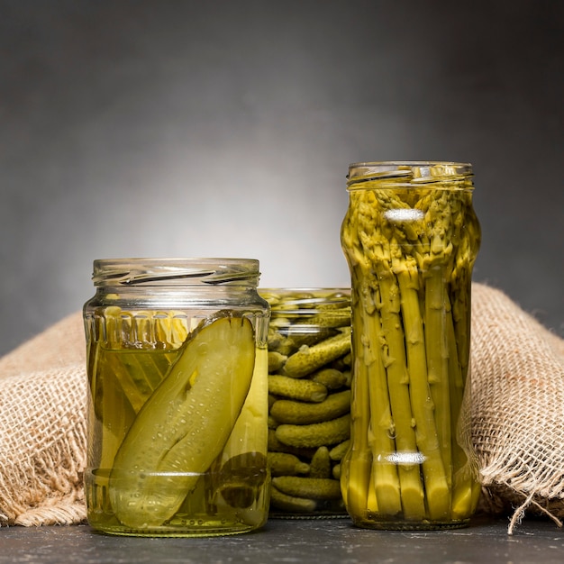 Vista frontale di barattoli di vetro con asparagi sottaceto e cetrioli