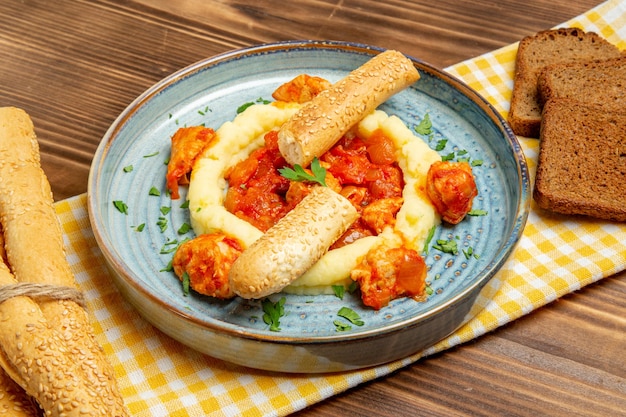 Vista frontale di carne condita con purè di patate e pagnotte di pane su pane di carne da scrivania in legno marrone cibo di patate