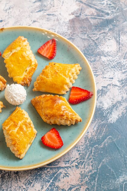 Vista frontale di deliziose torte dolci all'interno della piastra sulla superficie blu