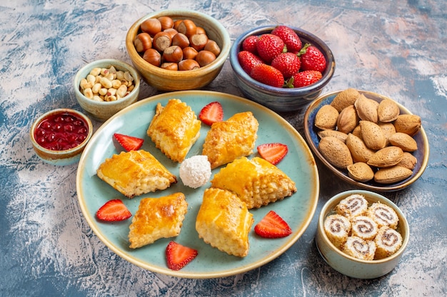 Vista frontale di deliziose torte dolci con frutta e noci sulla superficie blu