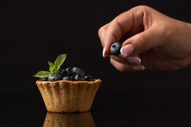 Vista frontale di dessert ai mirtilli con mano e menta