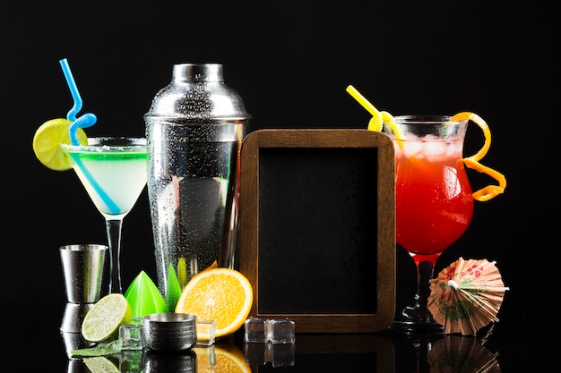 Vista frontale di diversi cocktail con shaker e lavagna