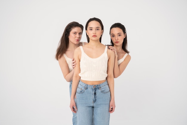 Vista frontale di donne in canotte e jeans che posano in ritratti minimalisti