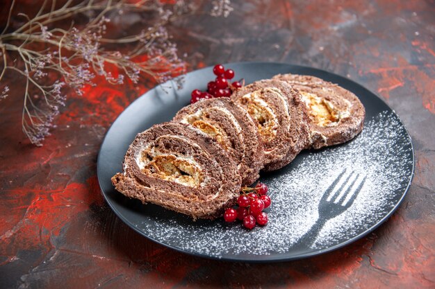 Vista frontale di gustosi rotoli di biscotti con frutta sulla superficie scura