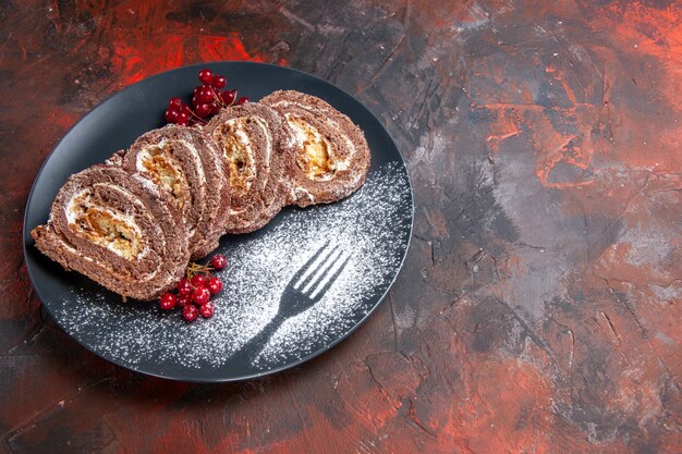 Vista frontale di gustosi rotoli di biscotti con frutta sulla superficie scura