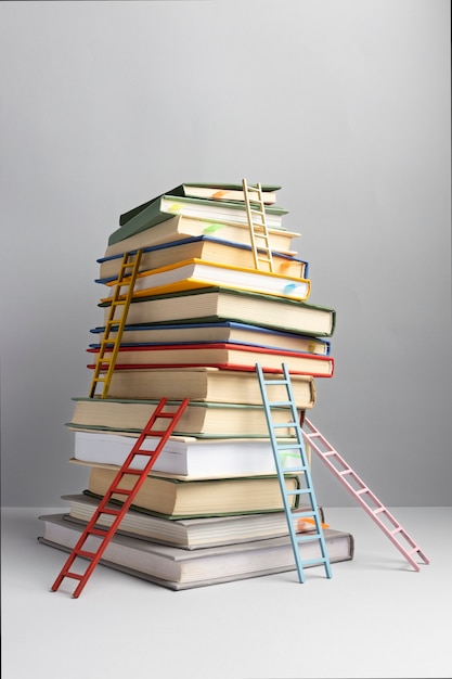 Vista frontale di libri impilati e scale con copia spazio per la giornata dell'istruzione