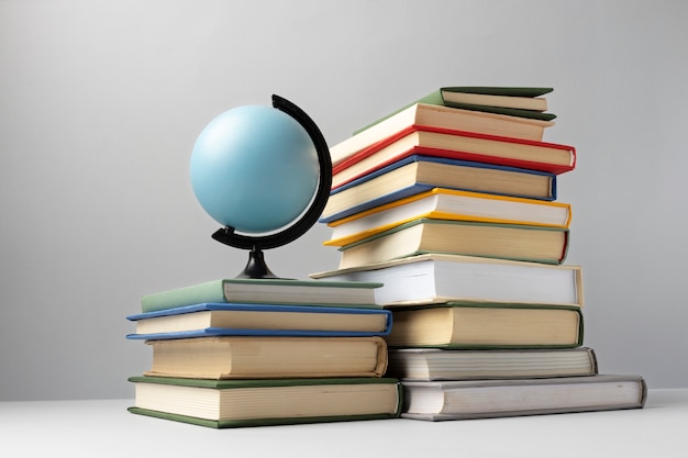 Vista frontale di libri impilati e un globo terrestre per la giornata dell'istruzione