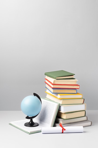 Vista frontale di libri impilati, un diploma e un globo terrestre con spazio per le copie per il giorno dell'istruzione