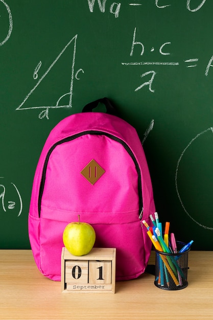 Vista frontale di nuovo allo zaino della scuola con la mela e le matite