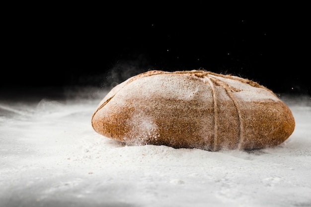 Vista frontale di pane e farina su fondo nero