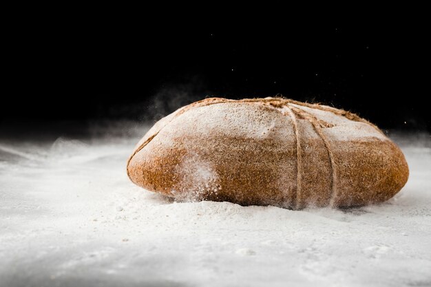 Vista frontale di pane e farina su fondo nero