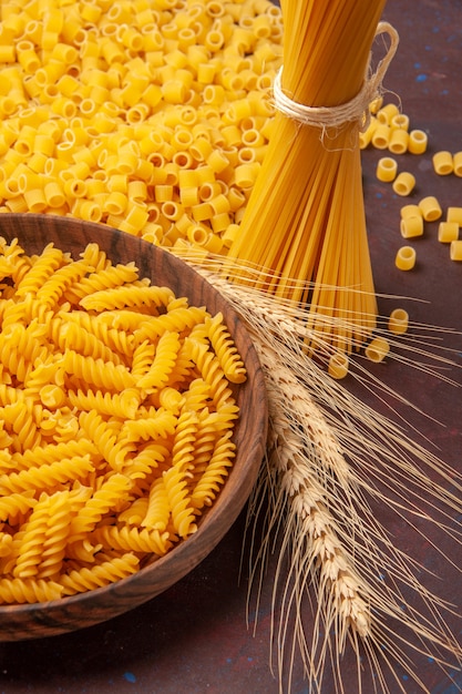 Vista frontale di pasta italiana cruda di forma diversa su uno spazio buio