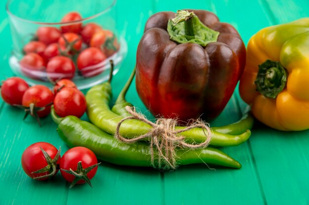 Vista frontale di peperoni e pomodori su superficie verde