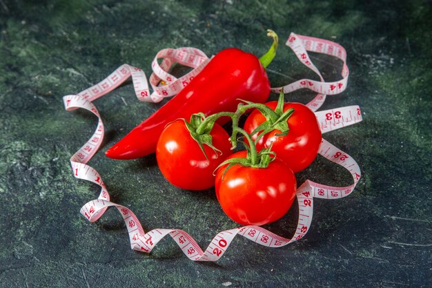 Vista frontale di pomodori freschi peperoni rossi e metro sulla superficie di colori scuri con spazio libero