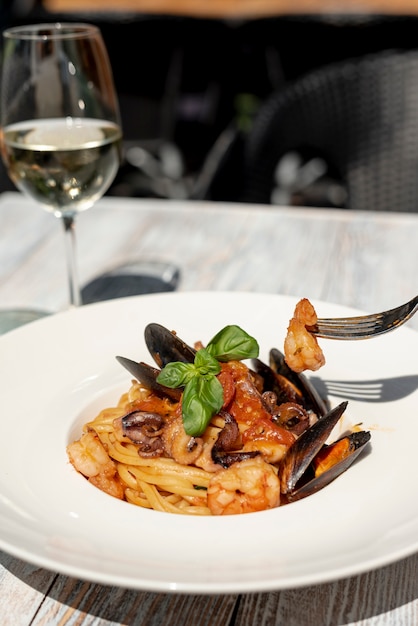 Vista frontale di spaghetti e vino sulla tavola di legno