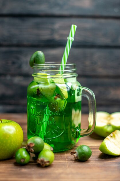 Vista frontale di succo di feijoa fresco all'interno della lattina con mele verdi su cocktail di foto a colori di frutta a barra scura