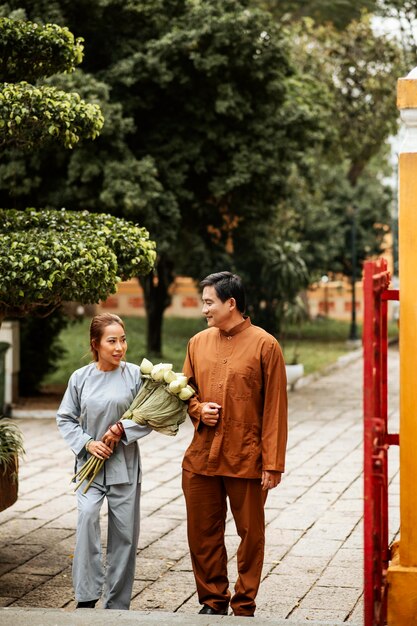 Vista frontale di un uomo e di una donna al tempio con incenso e bouquet di fiori