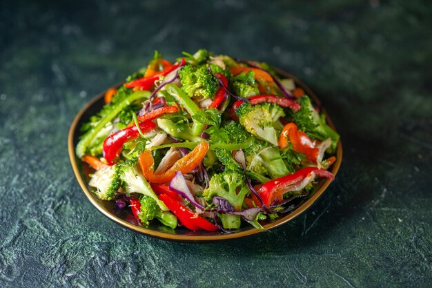 Vista frontale di una deliziosa insalata di verdure con vari ingredienti su sfondo scuro