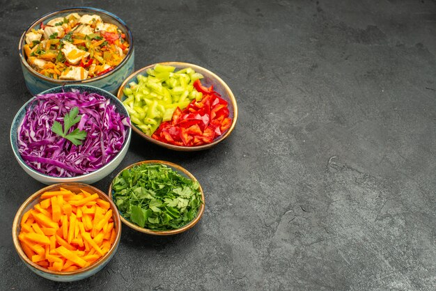 Vista frontale diverse verdure a fette con insalata di pollo sul tavolo scuro