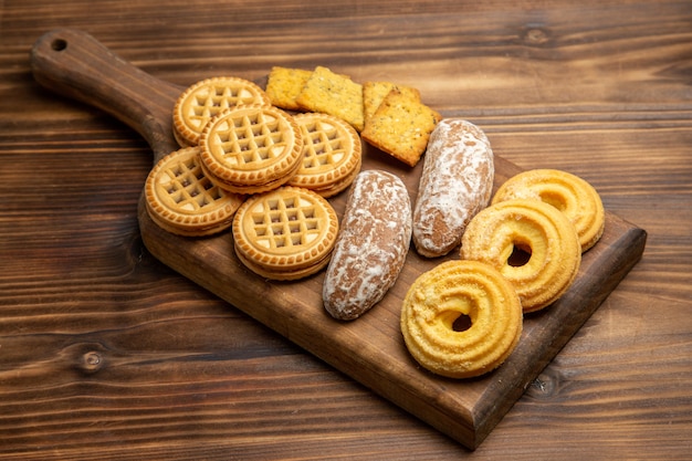 Vista frontale diversi biscotti dolci per il tè sullo zucchero biscotto biscotto tavolo marrone